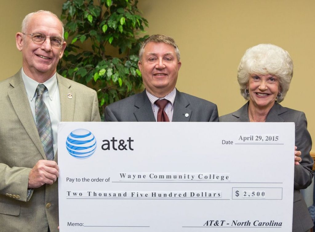Wayne County Board of Commissioners Chairman Wayne Aycock assists AT&T Regional Director for External Affairs John Lyon with the presentation of a $2,500 check to Wayne Community College President Kay Albertson. The contribution to the college’s general scholarship fund will be used to assist military veterans and their families.