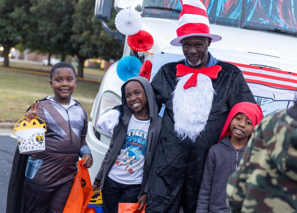 A man dressed as the Cat in the Hat stands with three boys.