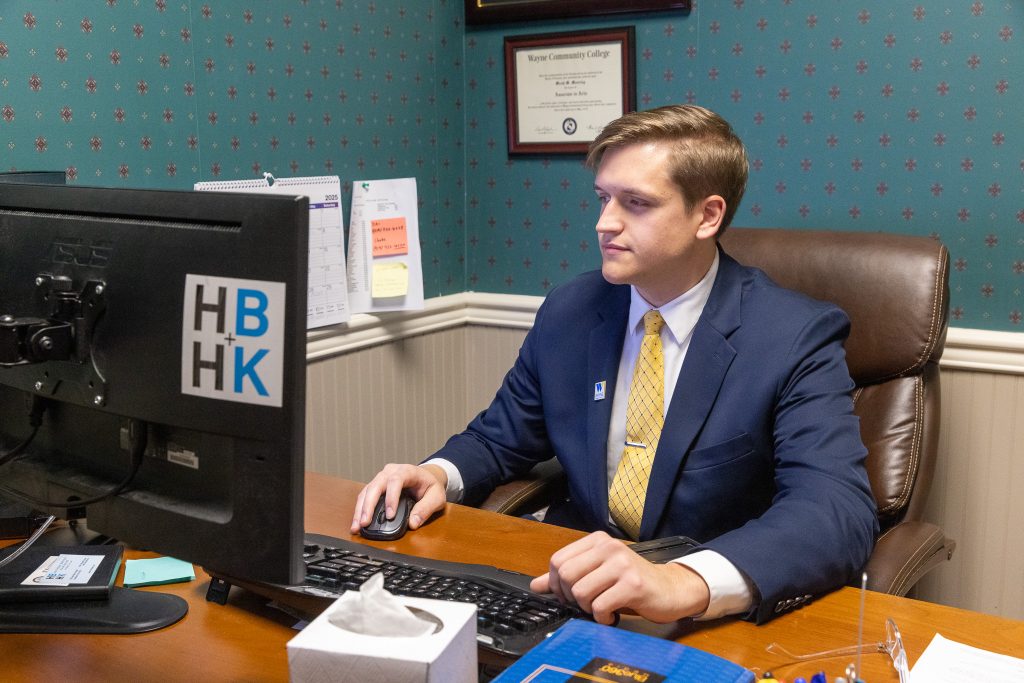 A man sits at a desk and works on his computer.