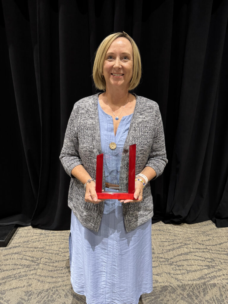 A woman holds a trophy.