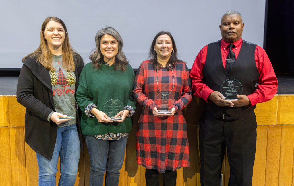 Four individuals stand and hold trophies.