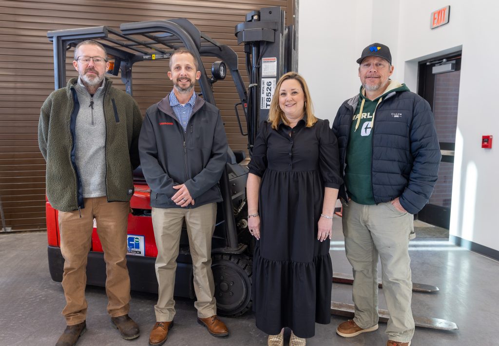 A group of individuals stand in front of a forklift.