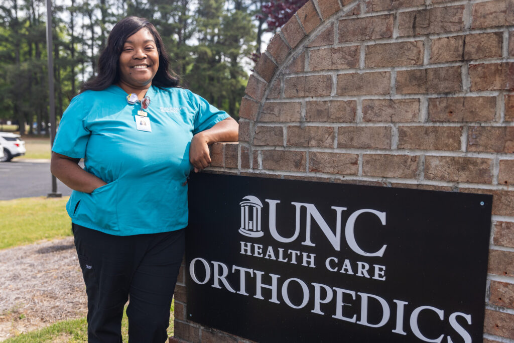 Teara Horton stands beside the sign of her place of work.