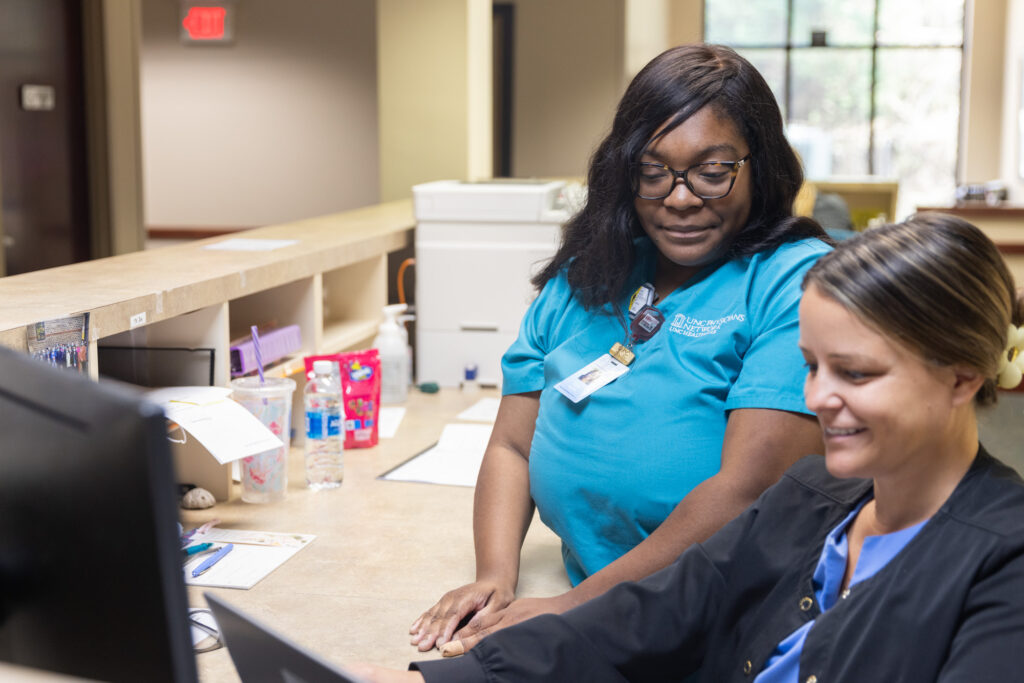 Teara Horton stands beside a coworker at her job.